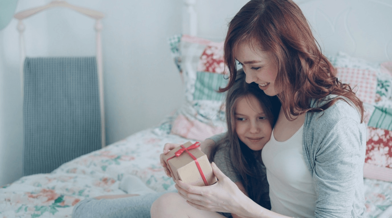 Eine Mutter überreicht ihrer Tochter ein schlicht eingepacktes Geschenk